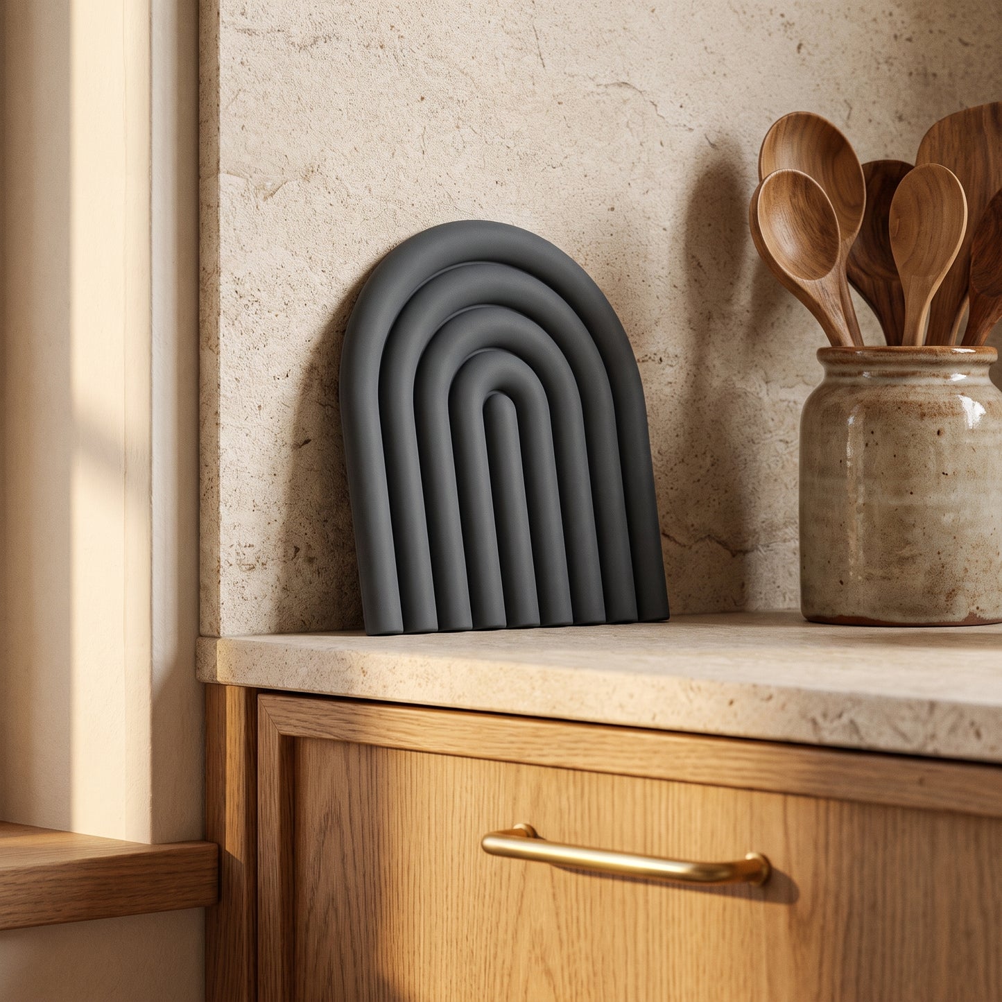 Vault™ Arch Trivet leaning against the stone backsplash in a warm Kopflo-style kitchen