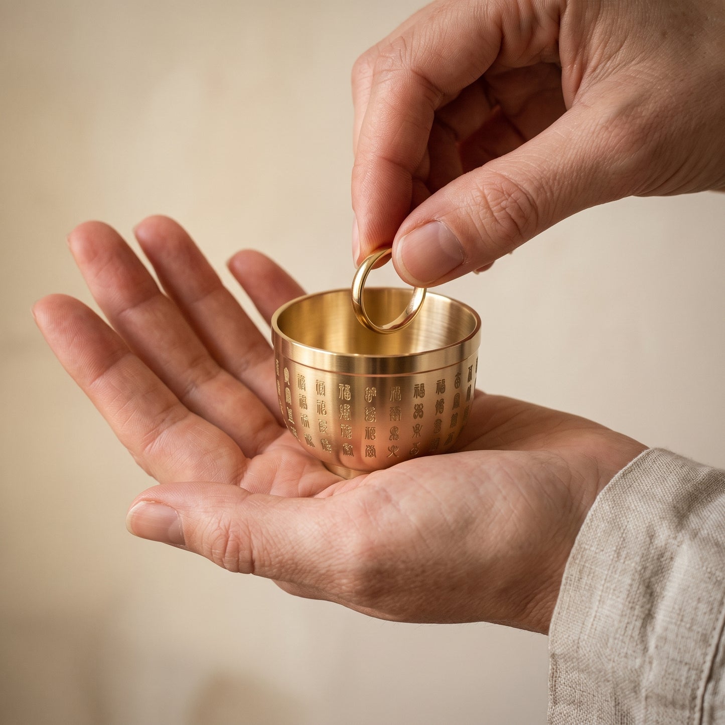 Thimble™ resting in an open palm while a ring is lowered into it, showing its true 4.5 cm size