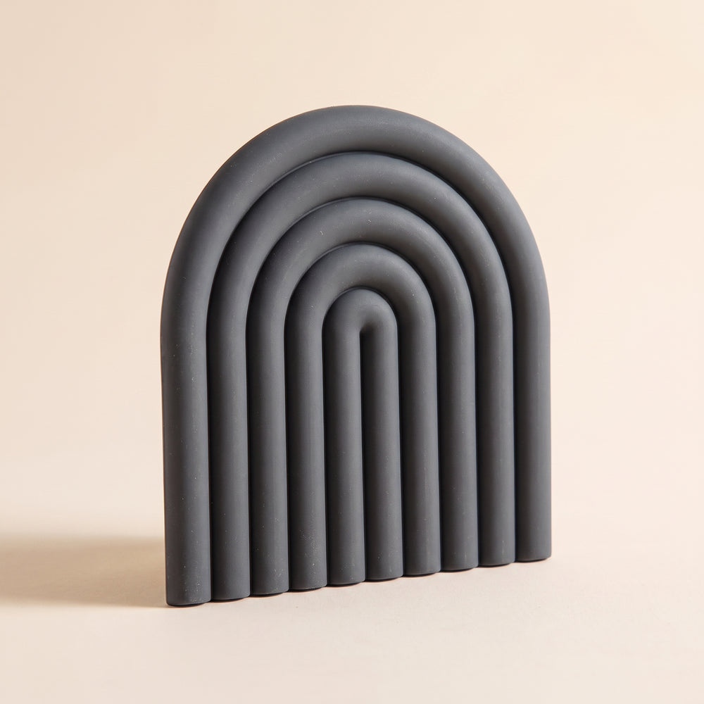 Vault™ Arch Trivet — charcoal ribbed silicone arch on warm cream background