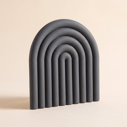 Vault™ Arch Trivet — charcoal ribbed silicone arch on warm cream background