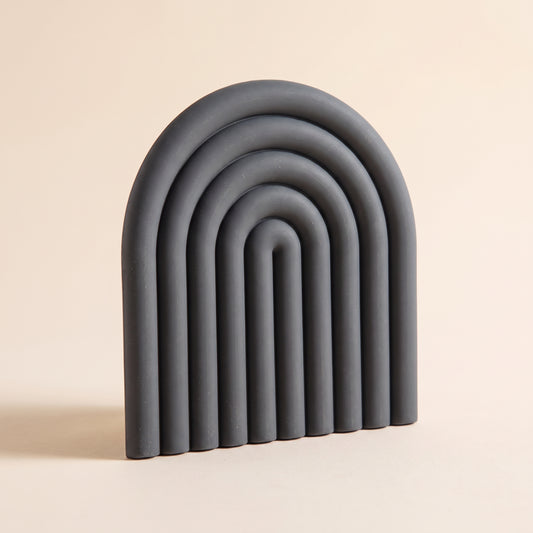 Vault™ Arch Trivet — charcoal ribbed silicone arch on warm cream background
