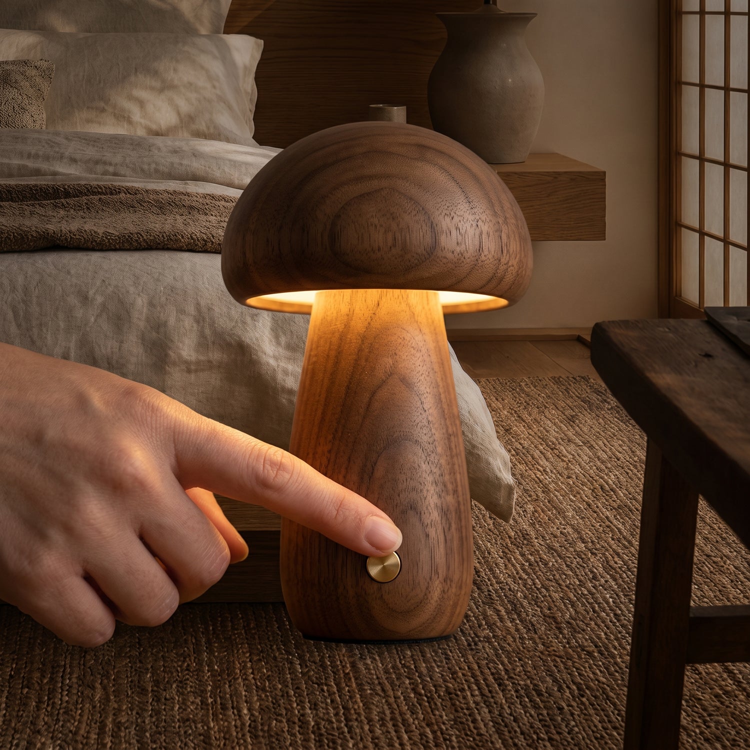 Pressing the brass button to dim the walnut Porcini™ Mushroom Lamp at night