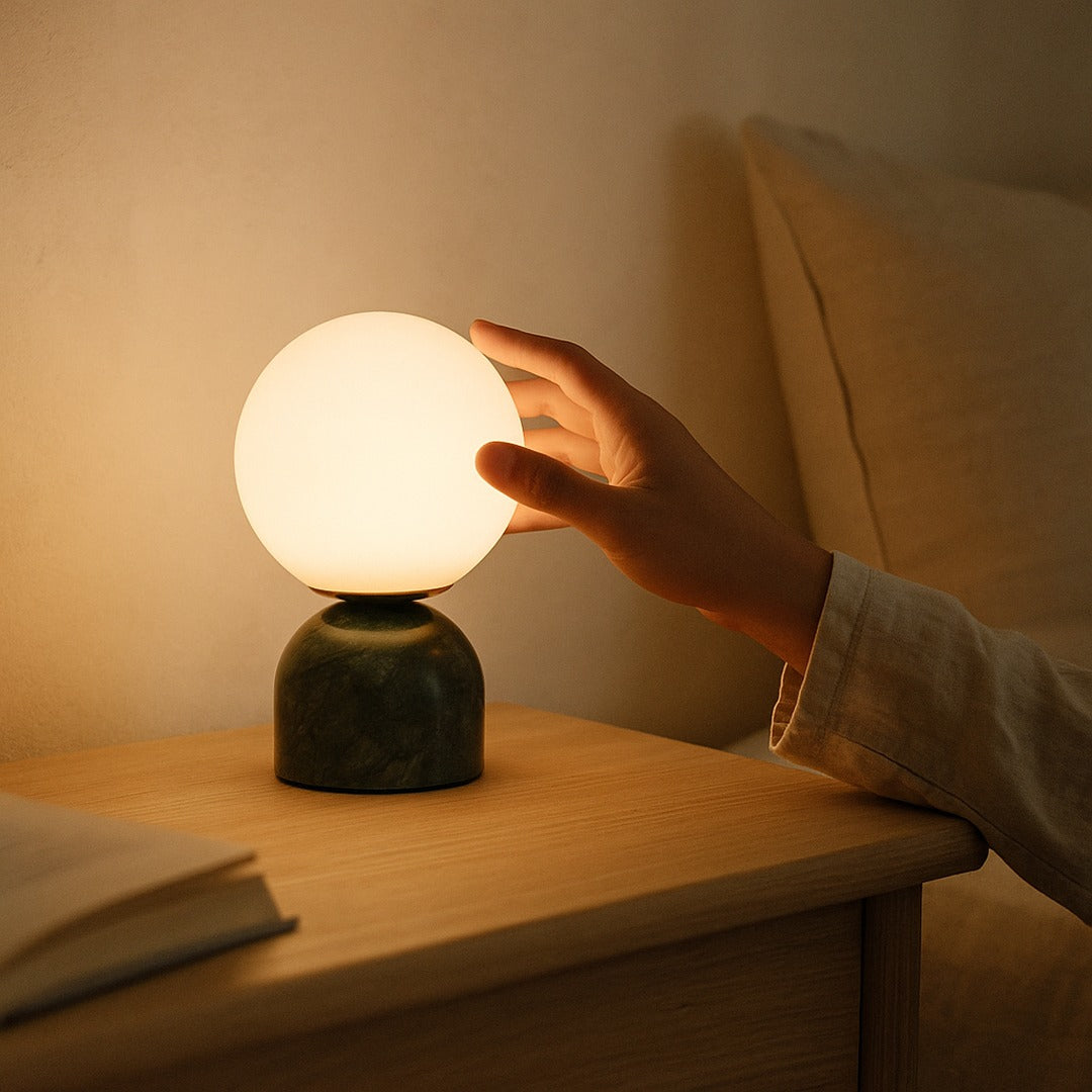 Hand reaching toward the glowing Pearl globe on an oak nightstand