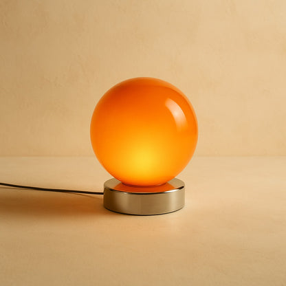 Ember glass globe lamp glowing on warm cream plaster