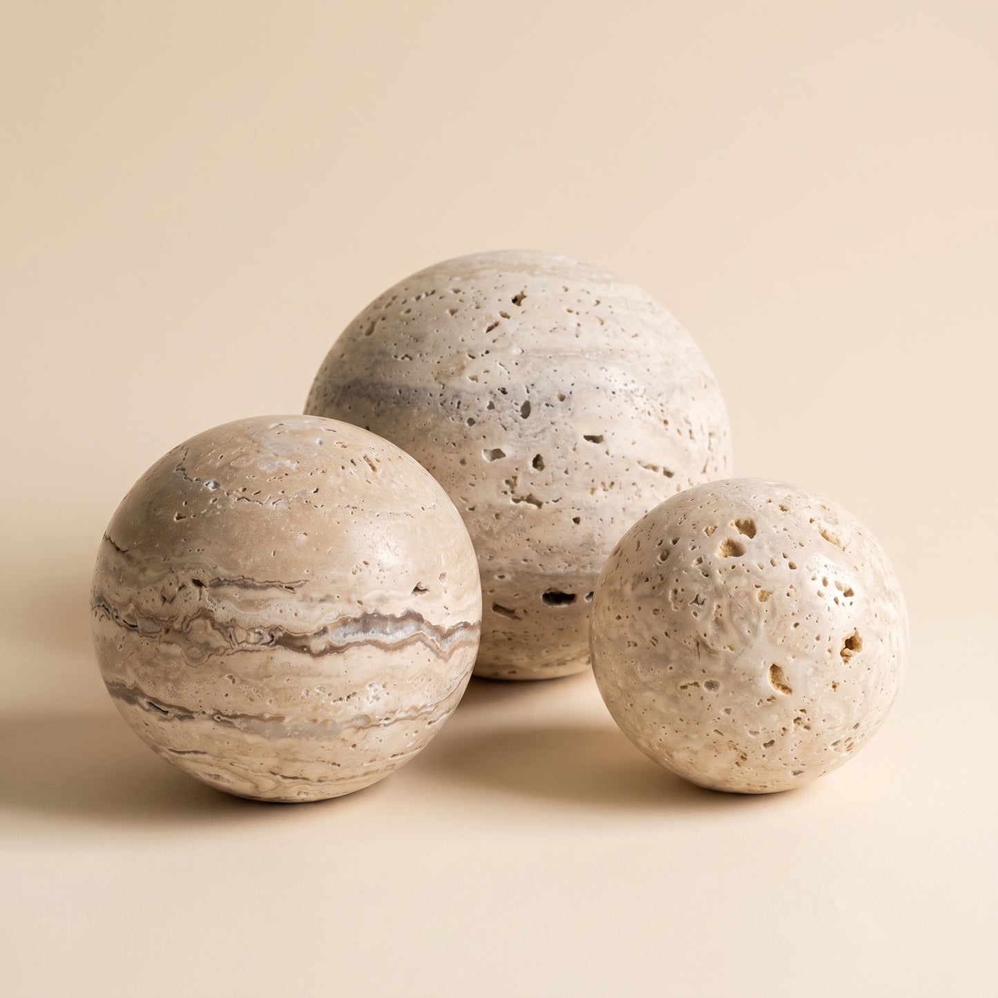 Tivoli™ Stone Sphere — three travertine spheres on warm cream background