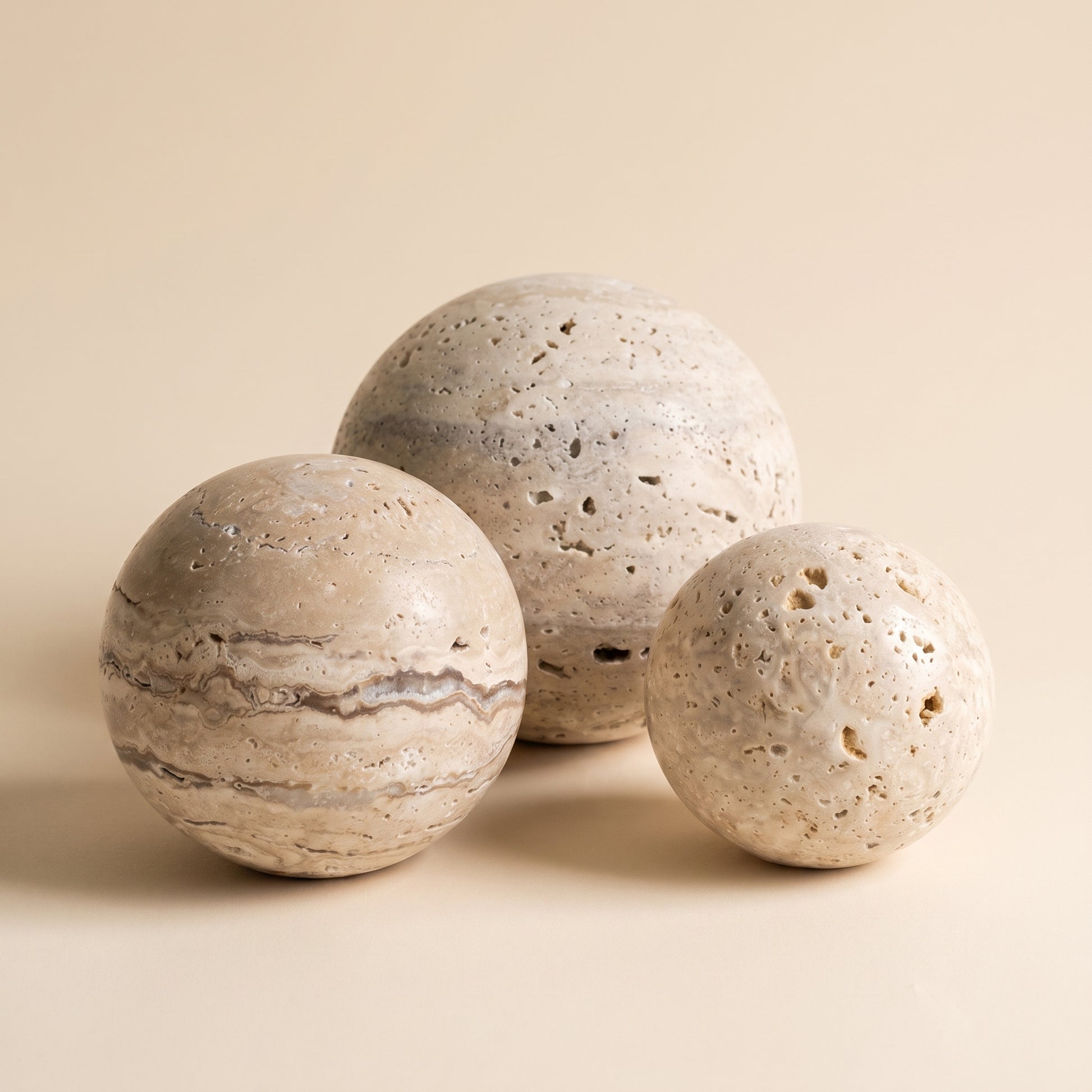 Tivoli™ Stone Sphere — three travertine spheres on warm cream background