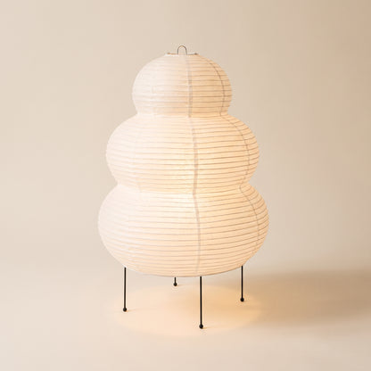 Cocoon™ Paper Table Lamp — triple-tier rice-paper lamp glowing on warm cream background