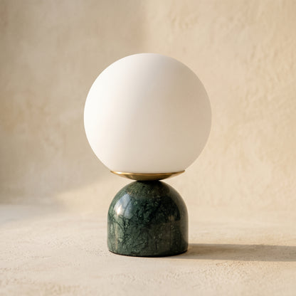 Cobble™ Marble Lamp — opal glass globe on a verde green marble dome base, on warm cream plaster