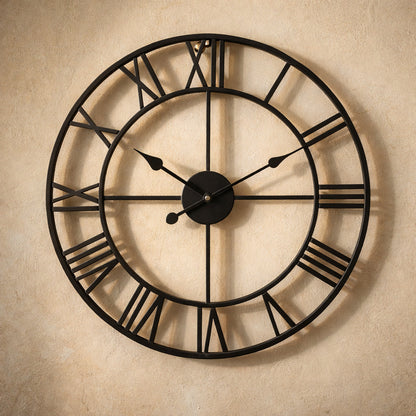 Forum wall clock in matte black on warm cream plaster, open skeleton iron frame with raised Roman numerals