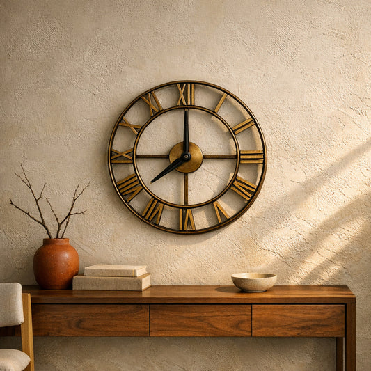 Forum wall clock in antique gold hung on a warm plaster wall above a walnut console table