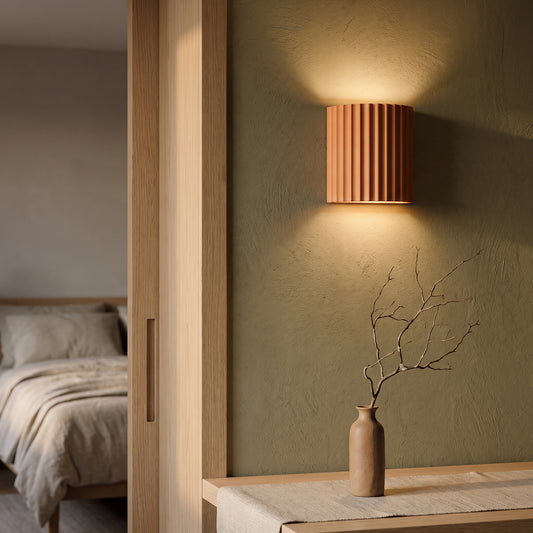 Terracotta Flute sconce washing warm light on an olive limewash wall beside an oak doorway