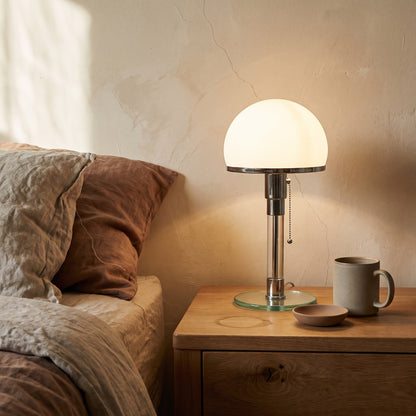Opal™ Table Lamp lit on an oak bedside table in a warm plaster bedroom