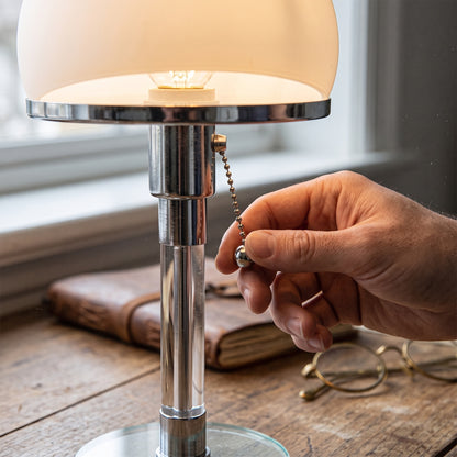 A hand pulling the ball-chain switch on the Opal™ Table Lamp