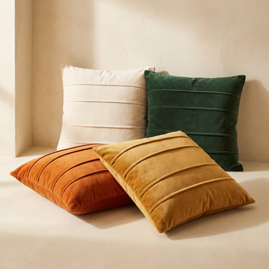 Pleat velvet cushion covers in ivory, forest, amber and ochre on warm cream plaster