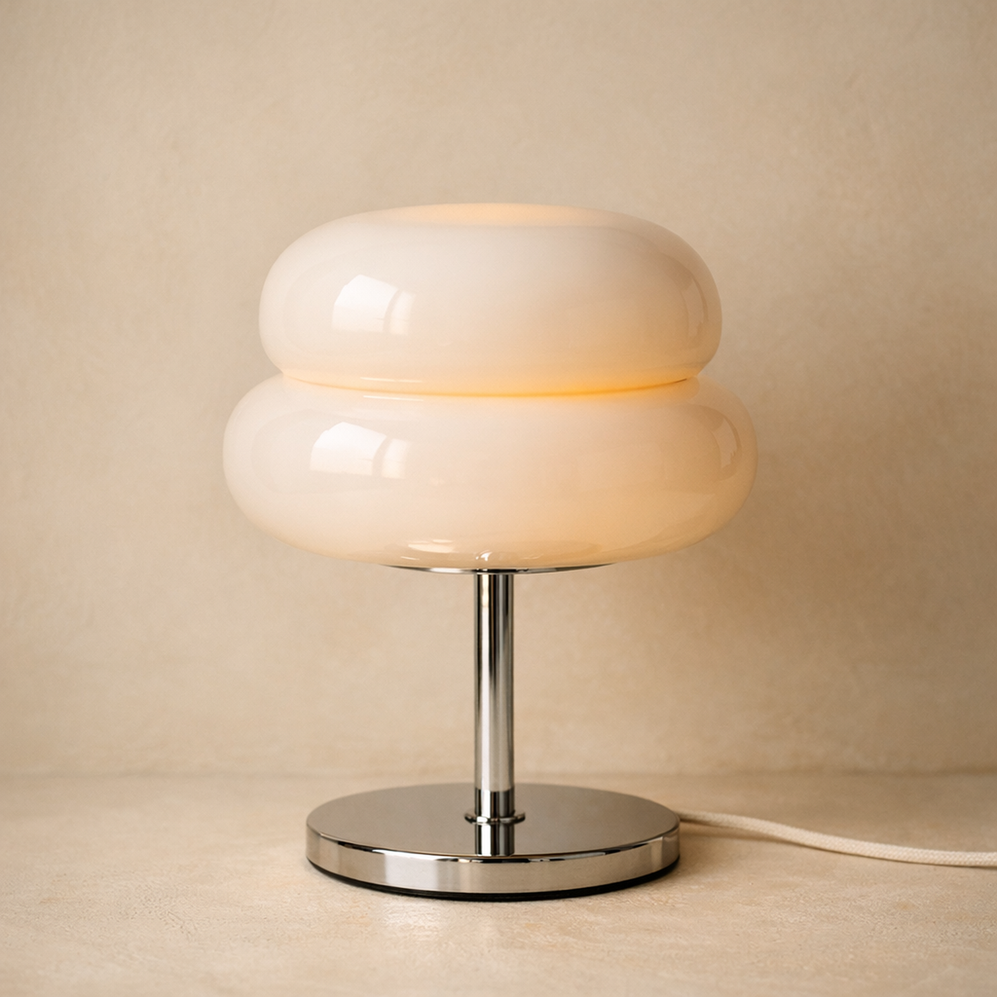 Sable glass table lamp with a two-tier opal glass macaron shade on a polished chrome stem, warm cream studio background