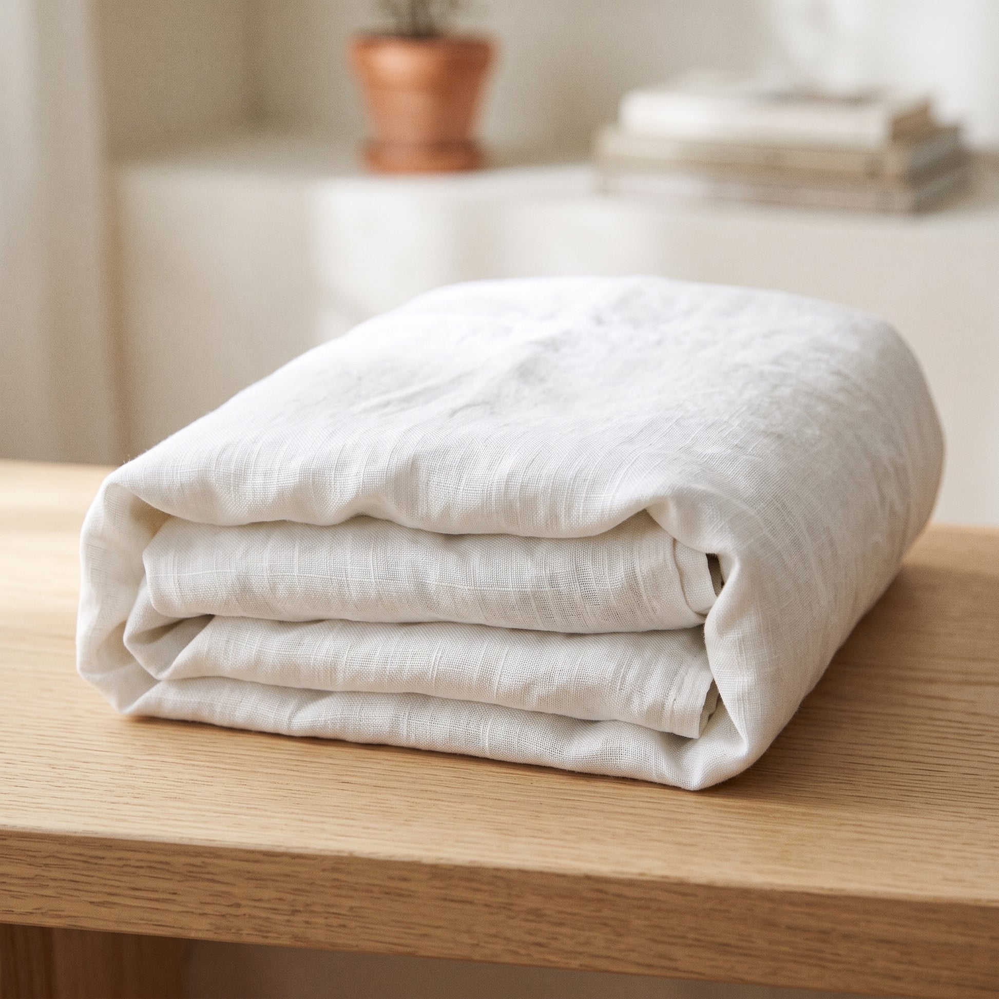 Slub white stonewashed French flax linen flat sheet folded on an oak bench