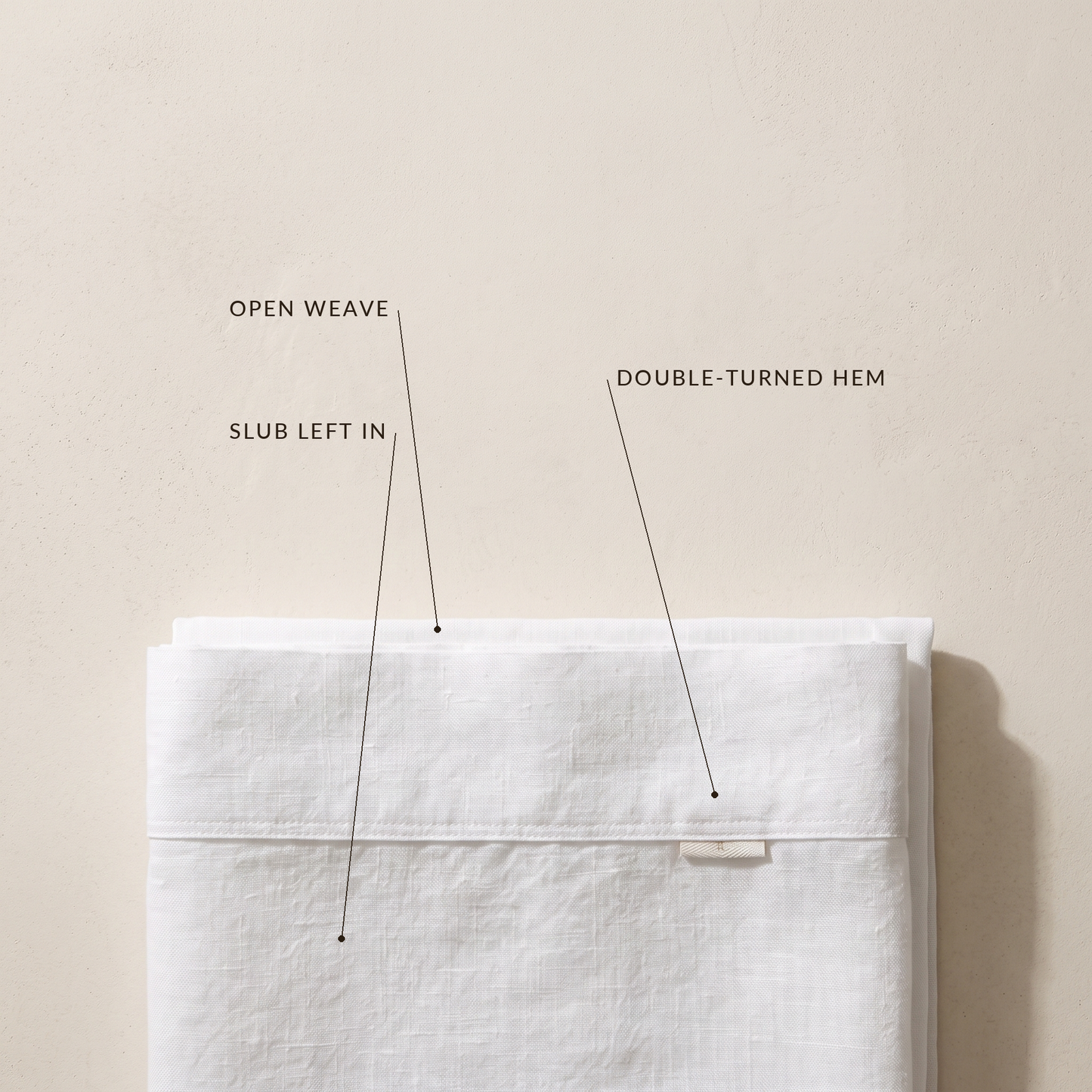 Detail of the open slub weave and double-turned hem on the white linen sheet