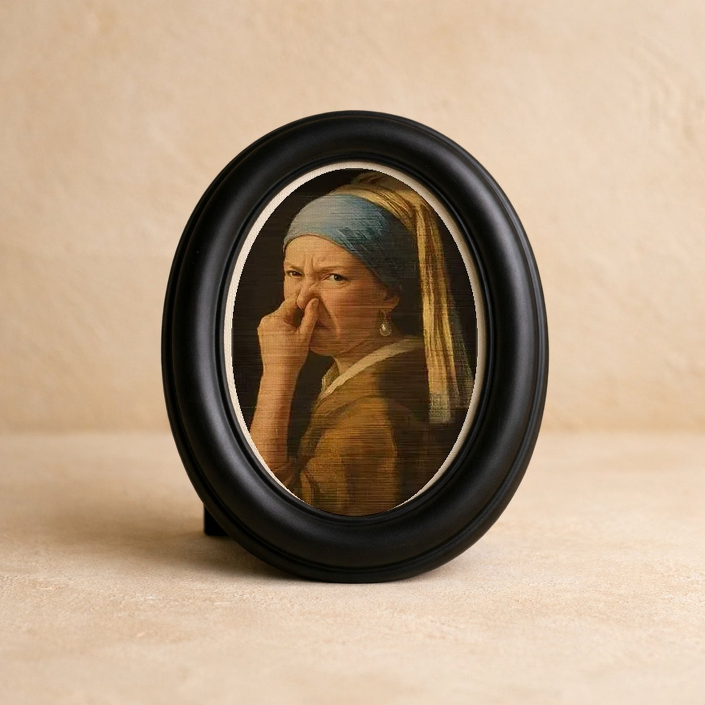 Wry Mini Portrait in a matte black oval frame on warm cream plaster