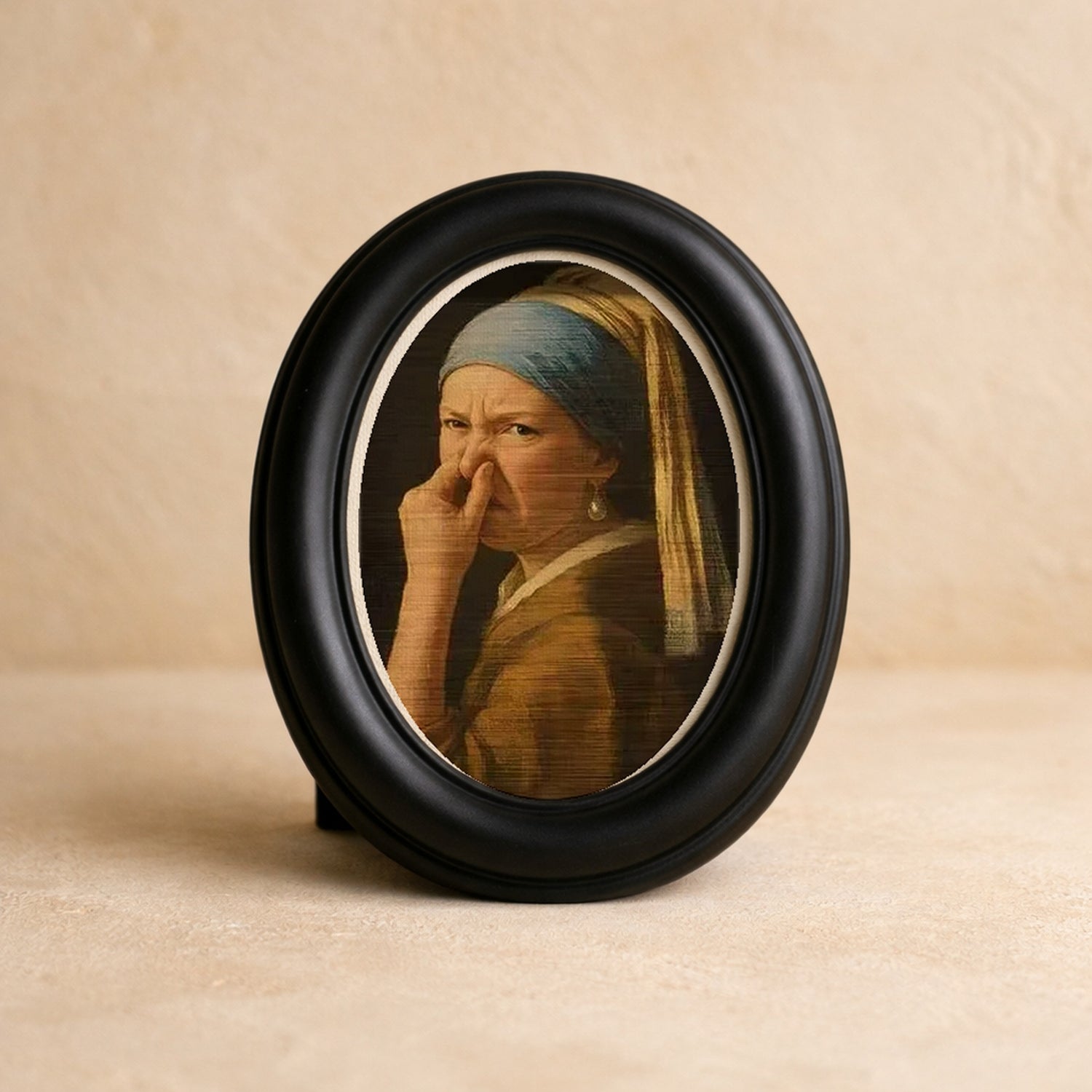 Wry Mini Portrait in a matte black oval frame on warm cream plaster
