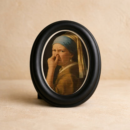 Wry Mini Portrait in a matte black oval frame on warm cream plaster